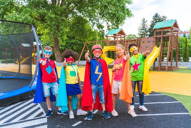 Wielorasowa grupa młodych uczniów noszących kostiumy superbohaterów i bawiących się na świeżym powietrzu