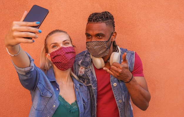 Wielorasowa para robi selfie z maską na twarzy - koncepcja Covid-19