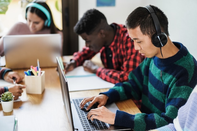 Wielorasowi studenci uczący się razem w bibliotece - Skoncentruj się na azjatyckich słuchawkach dla chłopców