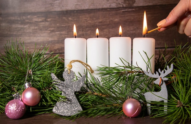 Wieniec adwentowy na Boże Narodzenie, dziewczyna zapala czwartą świecę