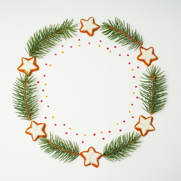 Wieniec bożonarodzeniowy z gałęzi jodły i ciasteczek w kształcie gwiazdy na białym tle