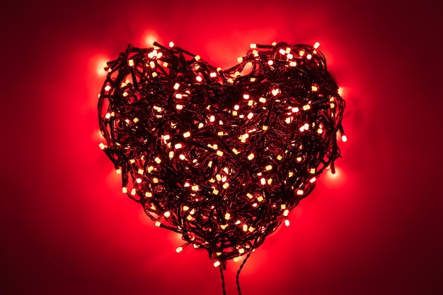 Wieniec w kształcie serca z czerwonymi żarówkami, splątanymi drutami, ciemne tło winietowe