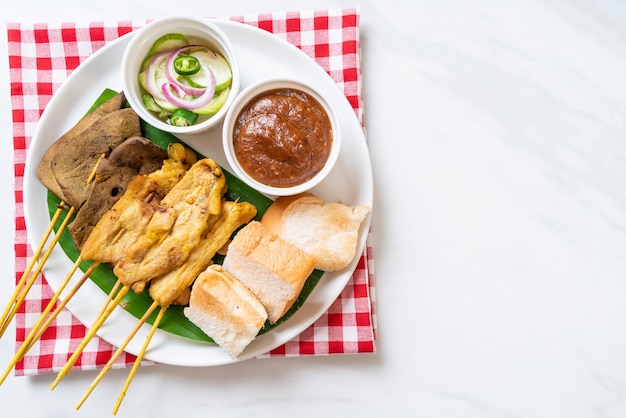 Wieprzowina Satay z sosem orzechowym i ogórkami, które są plasterkami ogórka i cebulą w occie