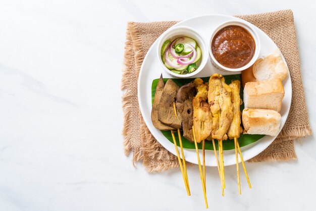 Wieprzowina Satay z sosem orzechowym i ogórkami, które są plasterkami ogórka i cebulą w occie