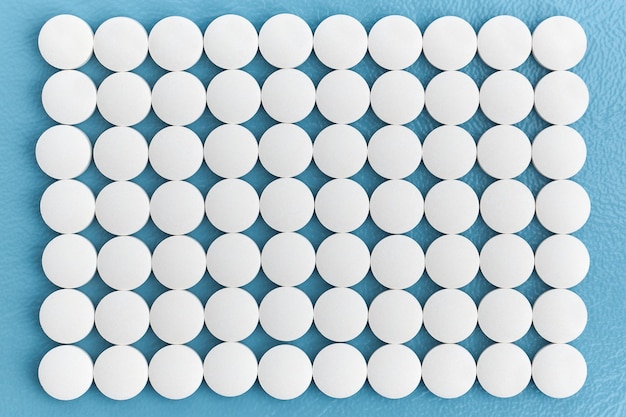 Wiersze białe tabletki medyczne na niebieskim tle farmaceutyki medyczne i chemia