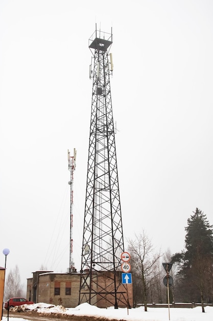 Zdjęcie wieża komunikacyjna na tle szarego nieba i drzew