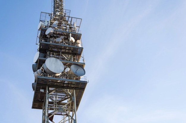 Wieża telekomunikacyjna z nadajnikami i antenami bezprzewodową komunikacją i koncepcją szerokopasmowych sieci komórkowych 5G jasne tło błękitnego nieba z miejscem na kopię
