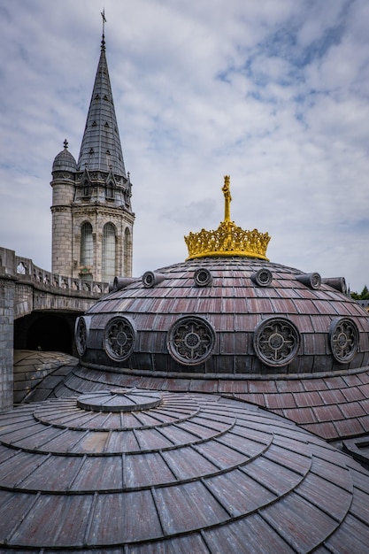 Wieże i dach ze złotym krzyżem neobizantyjskiej bazyliki Notre Dame de Lourdes we Francji