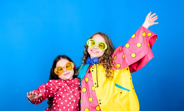 Więzy rodzinne Małe dziewczynki w płaszczu przeciwdeszczowym i okularach szczęśliwe małe dziewczynki w kolorowym płaszczu przeciwdeszczowym ochrona przed deszczem Tęcza jesień moda wesoły hipster dzieci siostrzane zabawy Całkowicie za darmo