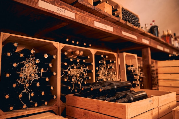 Winiarnia z butelkami napoju alkoholowego w drewnianych skrzynkach i półkach z etykietami rocznika