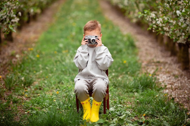 Winnica Ukraina 18 maja 2021 Mały chłopiec w żółtych butach fotografuje swoją matkę w kwitnącym wiśniowym ogrodzie