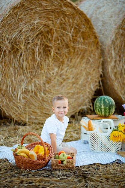 Winnica Ukraina 2 sierpnia 2022 Blond chłopiec siedzi na polu z arbuzem i uśmiecha się