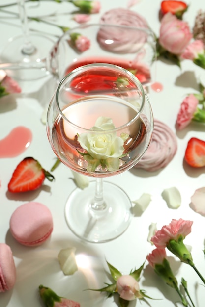 Wino, słodkie potrawy i kwiaty na białym stole