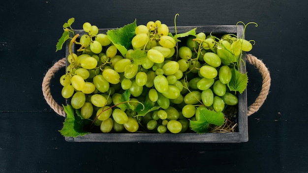 Winogrona w drewnianym pudełku Liście winogron Widok z góry Na czarnym tle Wolne miejsce na tekst