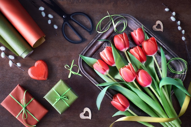 wiosenne dekoracje z zapakowanymi prezentami, kwiatami tulipanów i sercami