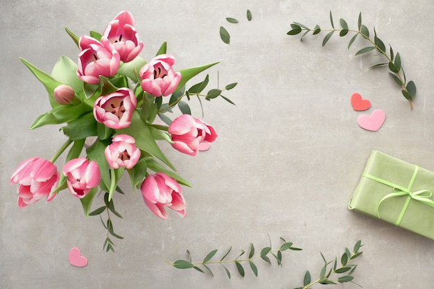 Zdjęcie wiosenne mieszkanie leżało z bukietem różowych tulipanów, liści eukaliptusa i pudełek na prezenty