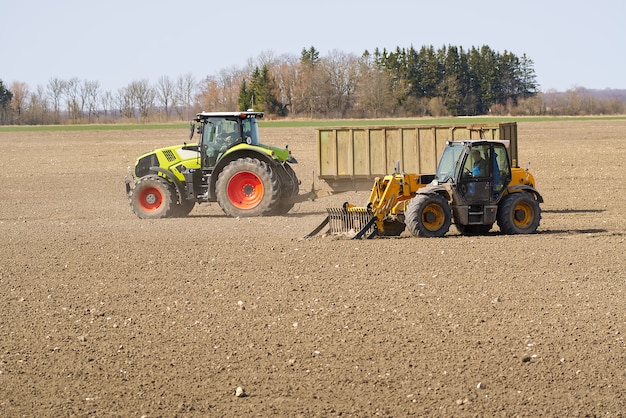 Zdjęcie wiosenne prace u rolnika w ciągniku przygotowujące pole do siewu ziemi rolniczej i traktora