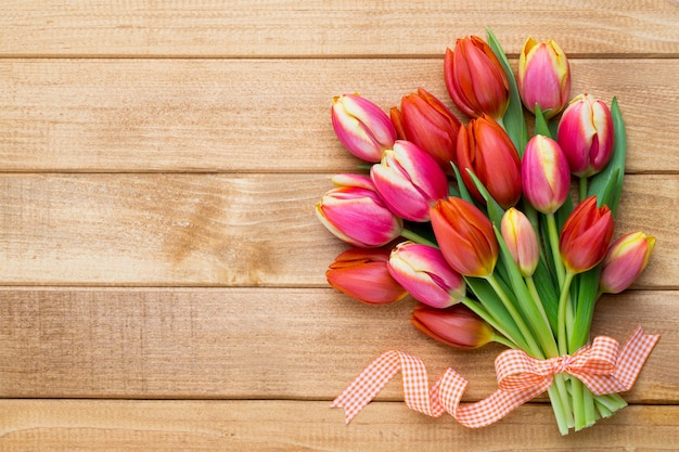 Wiosenne tulipany wielkanocne w wiadrze na drewniane tło.