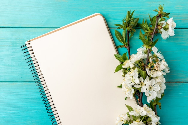 Zdjęcie wiosenny kwiat wiśni i notebook na niebieskim tle drewnianych.