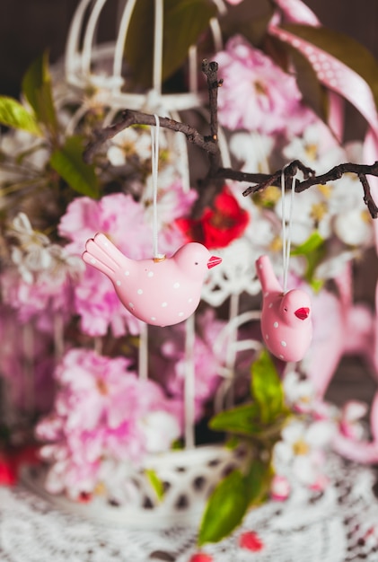 Wiosenny wystrój - różowe ptaszki na gałęzi w klatce shabby chic z kwiatami