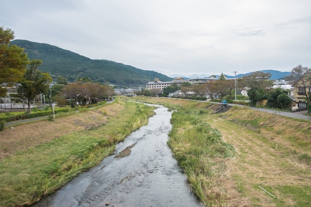 Wioska Yufuin, rzeka, góra Yufu i błękitne niebo z tłem chmur, Yufuin, Oita, Kyushu, Japonia