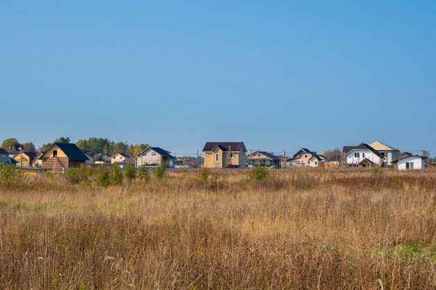 Wioska z domkami. Jesienny widok na nowoczesną wioskę domków w suchym żółtym polu. Rosja.