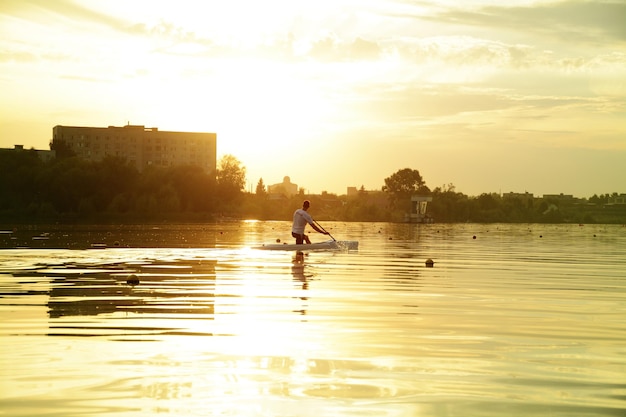 wioślarz sportowiec człowiek kajakarstwo, zachód słońca nad rzeką, trening sportowy.