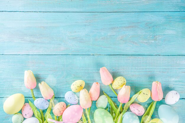 Wiosna I Wielkanoc Tło Wakacje Z Kwiatów Tulipanów, Kolorowe Pastelowe Jajka Na Niebieskim Widoku Z Góry Stołu. Kartkę Z życzeniami Wesołych świąt.