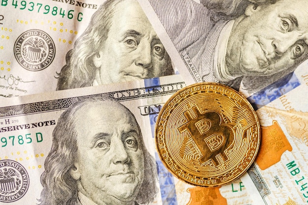 Wirtualne pieniądze złoty bitcoin na stodolarowych banknotach w tle Wymień bitcoin gotówkę na dolara