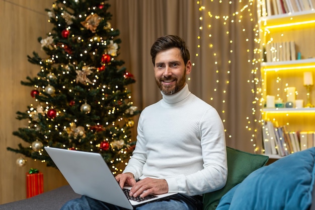 Wirtualne spotkanie na święta bożonarodzeniowy młody przystojny mężczyzna siedzi w domu na kanapie w pobliżu