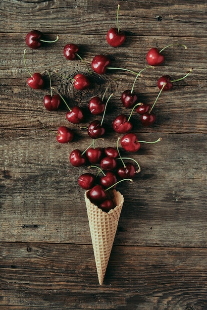 Wiśnie w rożku waflowym na drewnianym stole koncepcja zdrowej przekąski płaskiej świeckiej fotografii i treści na blog o żywności