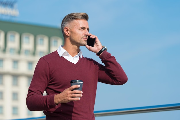 Witam Przystojny mężczyzna rozmawia przez telefon picie kawy na zewnątrz Odbieranie telefonu Marketing bezpośredni przez telefon komórkowy Połączenie z telefonem komórkowym Komunikacja biznesowa Nowa technologia Nowoczesne życie