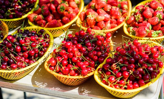 Witaminy i diety owoce sezonowe naturalne zakupy organiczne przydatne jedzenie zdrowy styl życia rynek rolny lato rynek jagodowy dojrzałe wiśnie wiśnia czerwona truskawka w koszu Jagoda tło