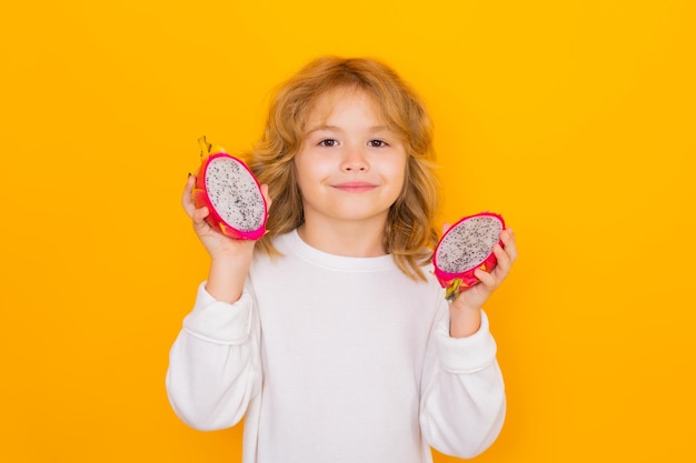 Witaminy i zdrowe owoce dla dzieci Kid trzymaj owoce smoka w studio Portret studyjny cute dziecka z owocami smoka samodzielnie na żółtym tle