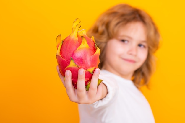 Witaminy i zdrowe owoce dla dzieci Kid trzymaj owoce smoka w studio Portret studyjny cute dziecka z owocami smoka samodzielnie na żółtym tle