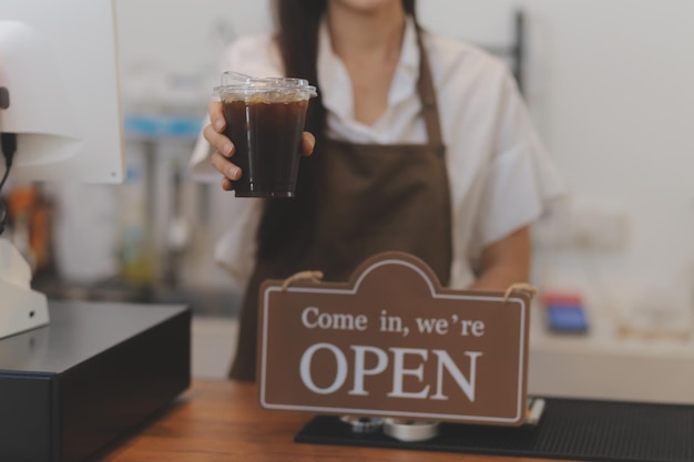 Witamy Otwarta kelnerka barista kobieta obracająca otwartą tablicę na szklanych drzwiach w nowoczesnej kawiarni kawiarni gotowa do obsługi kawiarni restauracja sklep detaliczny właściciel małej firmy koncepcja jedzenia i napojów