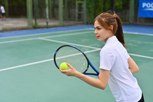 Wizerunek całkiem młodej tenisistki z rakietą serwującą piłkę podczas meczu