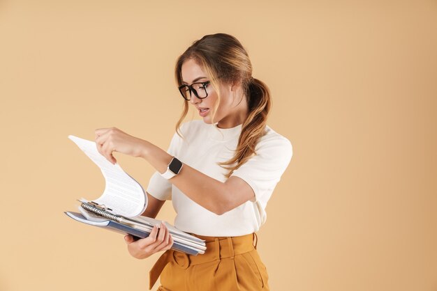 Wizerunek młodej bizneswoman noszącej okulary trzymającej schowek i księgi rachunkowe na białym tle