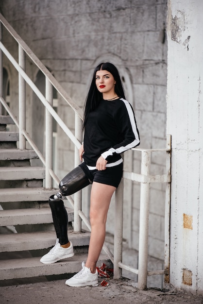 Wizerunek niepełnosprawna działająca dziewczyna z protetyczną nogą w sportswear chodzi w górę schodków w ulicie