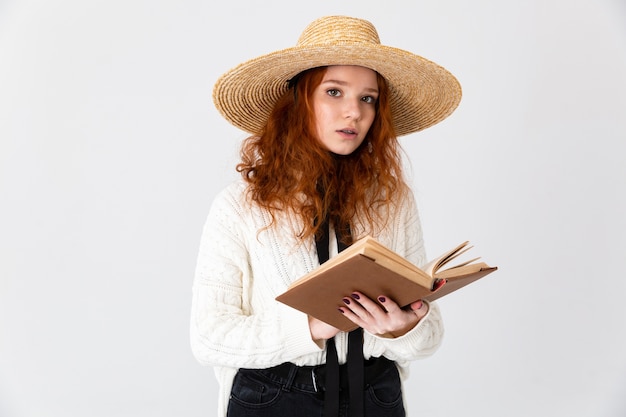 Wizerunek rudowłosy piękny młody ładny dziewczyna pozowanie na białym tle na tle białej ściany gospodarstwa książki do czytania.