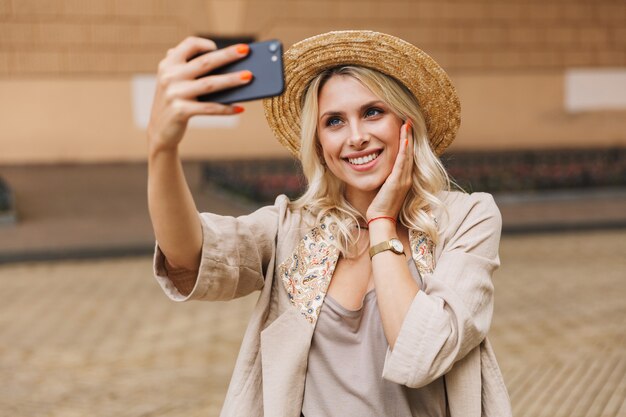 Wizerunek szczęśliwej młodej kobiety słodkie spacery na świeżym powietrzu wziąć selfie przez telefon komórkowy.