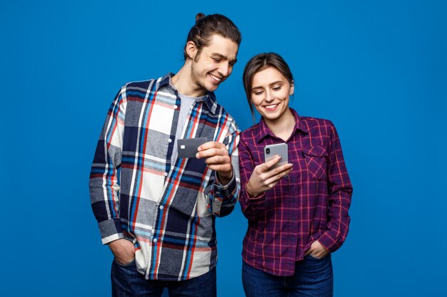 Wizerunek uśmiechnięty mężczyzna i kobieta w przypadkowej odzieży pozyci i mieniu telefony komórkowi z kredytową kartą