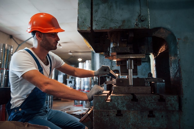 Wkłada Blachę Do Maszyny. Mężczyzna W Mundurze Pracuje Nad Produkcją. Nowoczesna Technologia Przemysłowa.