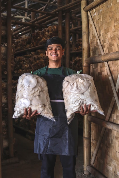 Właściciel firmy zajmującej się farmą grzybów trzymający worek boczniaków z zbioru grzybów.