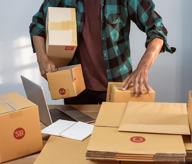 Właściciel małej firmy pakuje się w kartonowe pudełko w miejscu pracy Przycięte zdjęcie mężczyzny przygotowującego paczkę