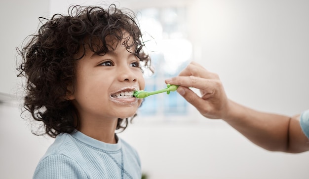 Właściwe mycie zębów dziecka pomaga zapobiegać próchnicy i infekcjom Zdjęcie przedstawiające ojca myjącego zęby małego synka w łazience w domu