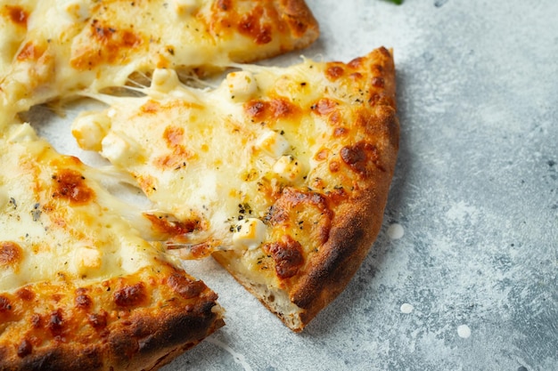 Włoska pizza cztery sery z rozciągającym się serem i bazylią na jasnym betonowym tle