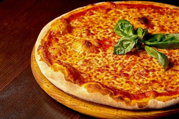 Włoska pizza Margherita z pomidorami i serem na drewnianej desce. Kuchnia włoska. Zbliżenie