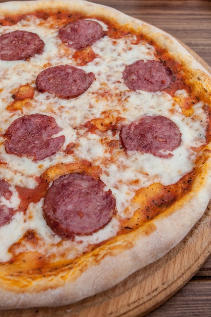 Włoska pizza Pepperoni z salami na ciemnym tle drewnianych widok z góry. Tradycyjne włoskie jedzenie. Popularne jedzenie uliczne.