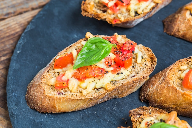 Włoski bruschetta z pieczonymi pomidorami, mozzarellą i